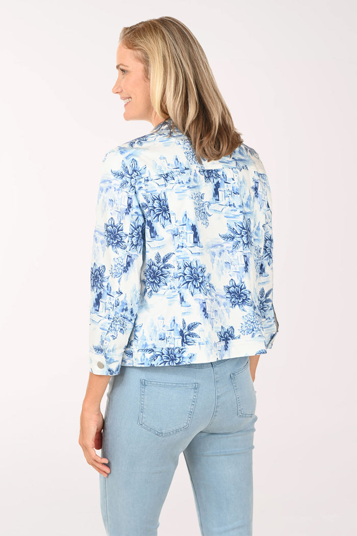 Woman wearing a white denim jacket with a blue floral pattern.