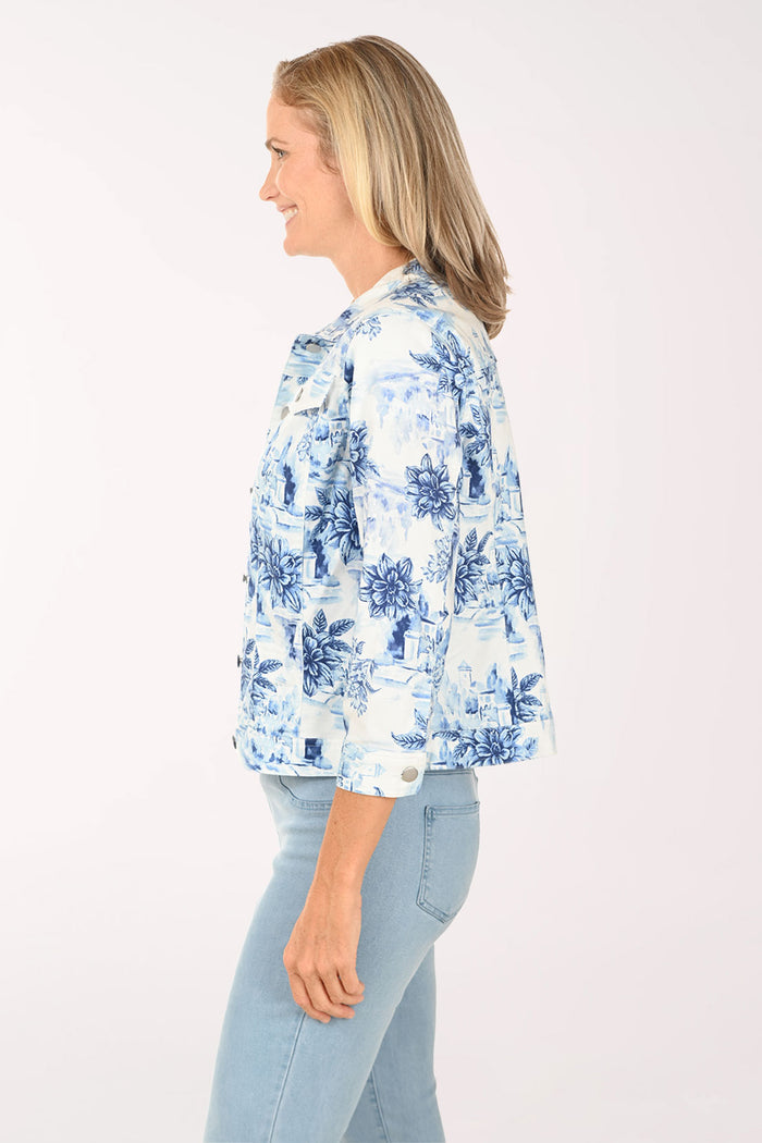 Woman wearing a white denim jacket with a blue floral pattern.
